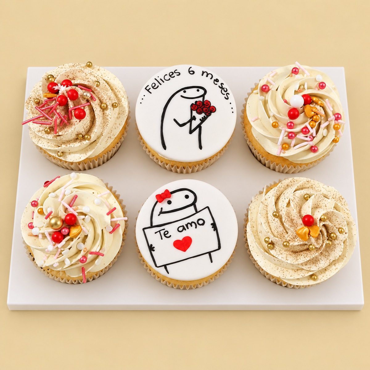Six anniversary cupcakes with ivory swirls, red and gold sprinkles, and two illustrated message toppers